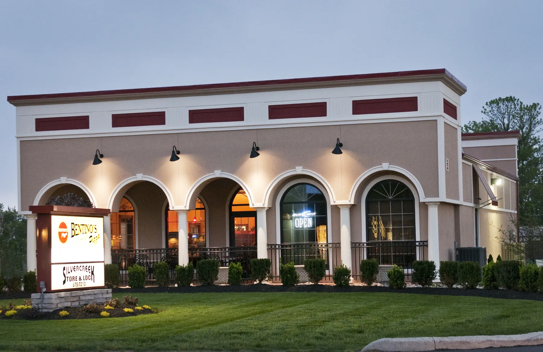 Bentino's Pizza at golden hour — stucco arches, red trim, lit OPEN sign