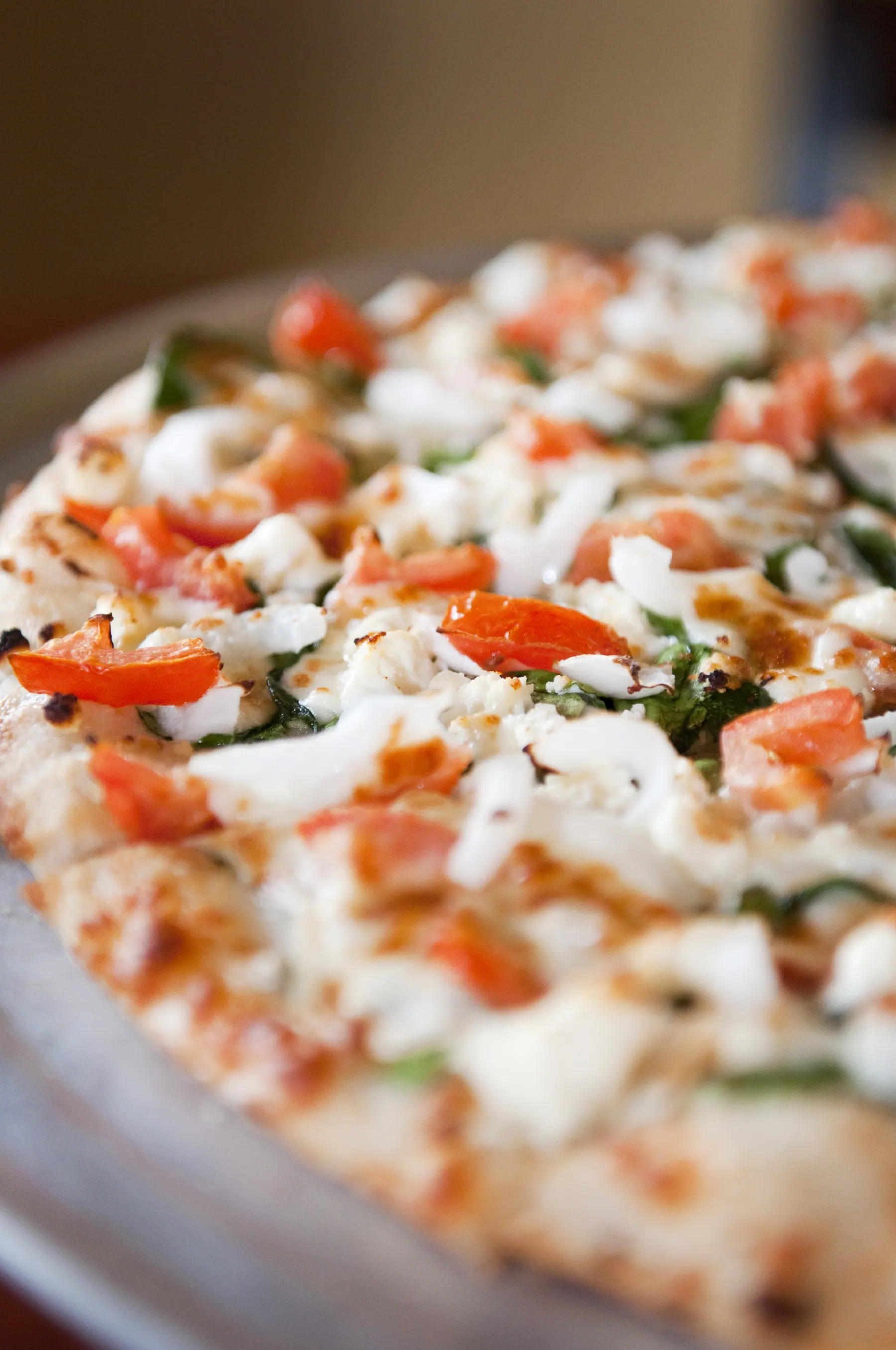 A fresh hand-tossed white pizza from Bentino's — feta, spinach, tomato, blistered crust