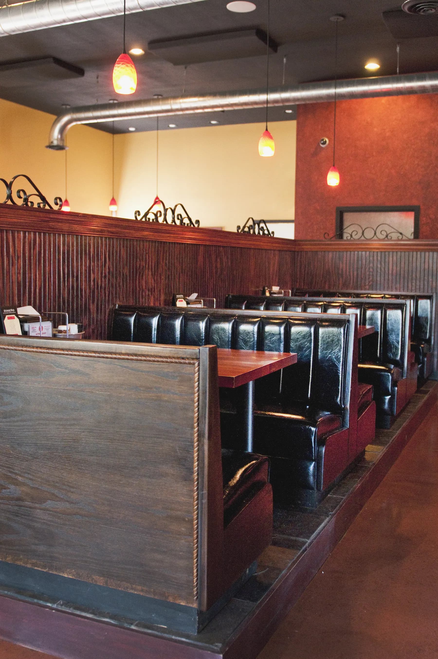 Inside Bentino's dining room — leather booths, warm pendant lights, exposed pipe ceiling